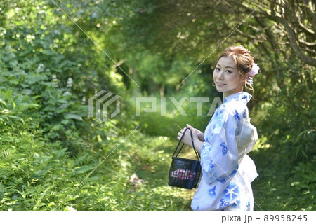 緑の森林を背景にポーズをとり微笑む浴衣を着た若く美しい女性 89958245