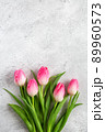 Bouquet blooming pink tulips flowers with green leaves on gray concrete background flat lay with copy space for congratulations, advertising or design. Minimalism concept. 89960573