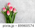 Bouquet blooming pink tulips flowers with green leaves on gray concrete background flat lay with copy space for congratulations, advertising or design. Minimalism concept. 89960574