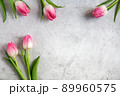 Blooming pink tulips flowers with green leaves on gray concrete background flat lay with copy space for congratulations, advertising or design. Minimalism concept. 89960575