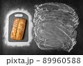 Top view of baking dark background withwith fresh whole loaf of bread and flour applied to place under the text and along contour of cutting board. 89960588