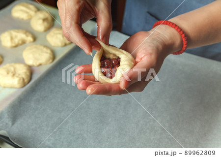 Pastry chef puts a spoonful of cherry in prepared bread dough Pastry chef puts a spoonful of cherry in prepared bread dough 89962809