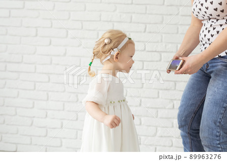 Child with cochlear implant hearing aid having fun with mother in room background with copy space and place for advertising - diversity and deafness treatment and medical innovative technologies 89963276