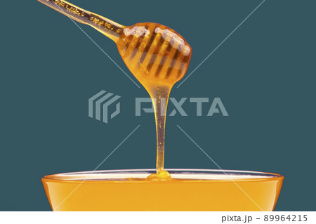 fresh honey drips from a spoon into a plate. organic vitamin health food 89964215