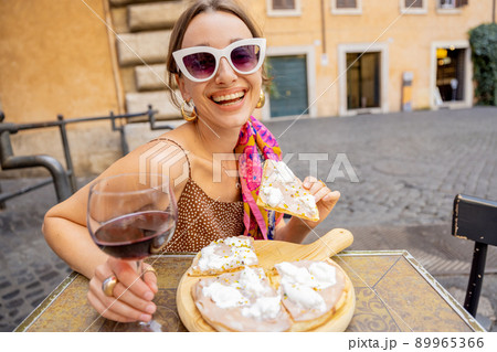 Woman eating pizza at italian restaurant outdoors 89965366