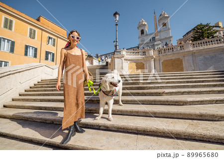 Woman running with her dog on famous Spanish steps in Rome 89965680