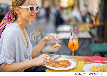 Woman eating italian pasta at restaurant on the street in Rome 89965972