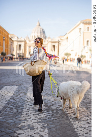 Stylish woman walks with a dog on the street in Rome 89965991