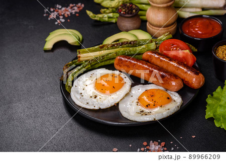 A delicious nourishing breakfast with fried eggs, sausages, asparagus, tomatoes, avocado, spices and herbs A delicious nourishing breakfast with fried eggs, sausages, asparagus, tomatoes, avocado, spices and herbs 89966209