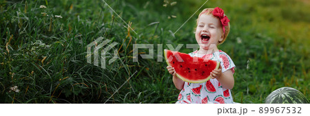 Little girl in a dress eats a watermelon at a picnic. 89967532