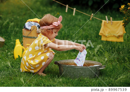 Little cute girl wipes her forehead after finishing washing in nature. 89967539