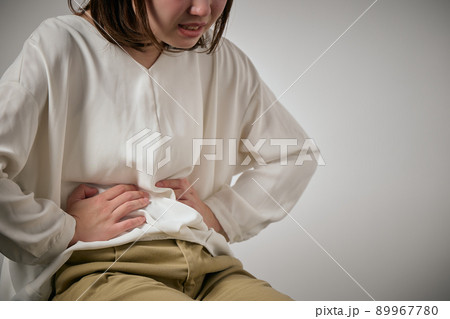 お腹が痛くて手でおさえる若い女性 お腹が痛くて手でおさえる若い女性 89967780