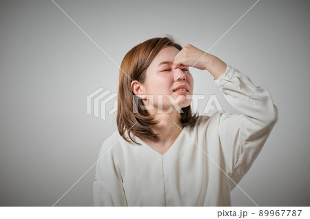 眉間が痛くて指でおさえる若い女性 89967787