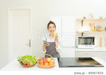 スマホを持つ女性　キッチン 89967850