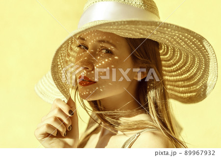 Attractive cheerful woman portrait in summer. Beautiful freckled girl in straw hat. Looking at camera. Isolated on yellow background in studio shot Attractive cheerful woman portrait in summer. Beautiful freckled girl in straw hat. Looking at camera. Isolated on yellow background in studio shot 89967932