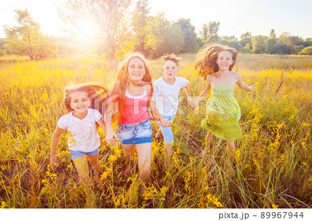 four happy beautiful children running playing moving together in the beautiful summer day. jumping and looking at camera with happiness and toothy smile. four happy beautiful children running playing moving together in the beautiful summer day. jumping and looking at camera with happiness and toothy smile. 89967944