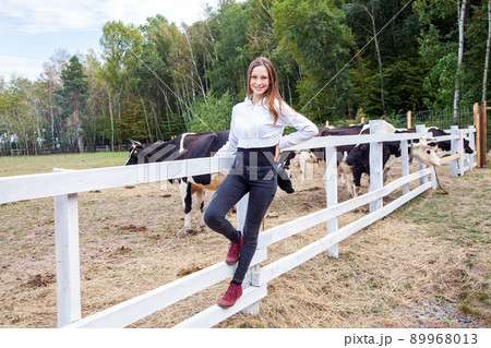 Beautiful young adult girl posing under milk farm. Outdoor 89968013