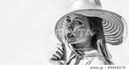 Portrait of beautiful sensual brunette young woman with makeup looking at camera with passion, holding hat, light through hat falls on face. Indoor studio shot isolated on light background copyspace. Portrait of beautiful sensual brunette young woman with makeup looking at camera with passion, holding hat, light through hat falls on face. Indoor studio shot isolated on light background copyspace. 89968076