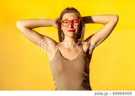 Happiness young adult brunette woman relaxed. Crossed hands under head, and looking at camera. Yellow background, studio shot Happiness young adult brunette woman relaxed. Crossed hands under head, and looking at camera. Yellow background, studio shot 89968409
