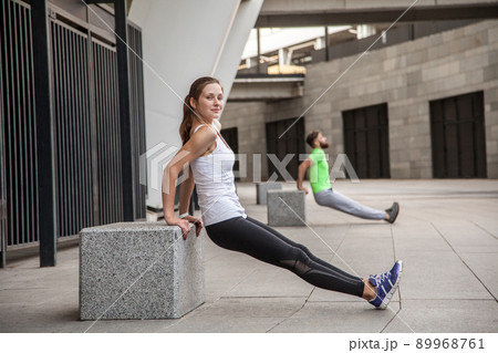 fitness, sport, exercising, training and people concept - couple doing triceps dip exercise on city street bench. 89968761