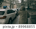 Traveling young woman in green raincoat with hood walking down street 89968855
