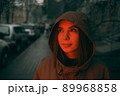 Young happy woman wearing raincoat is feeling free and smiling under the rain. red light 89968858