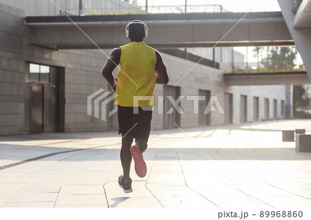 Young fit man in yellow t-shirt running sunset outdoors, autumn running, attractive dark skinned runner jogging fast in the park with beautiful light on background, sport concept 89968860