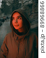 Young happy woman wearing raincoat is feeling free and smiling under the rain. red light 89968866