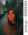 Young happy woman wearing raincoat is feeling free and smiling under the rain. red light 89968868
