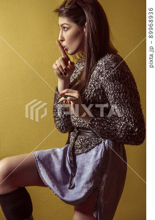 Beautiful young asian model in blue denim skirt and black blouse and fashion makeup posing sitting on stepladder and looking at camera. Studio shot. High-fashion photo. 89968936