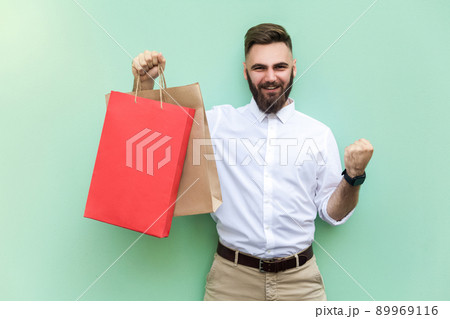 Shopping, Young adult successful businessman looking at camera and toothy smile. Indoor, studio shot. 89969116