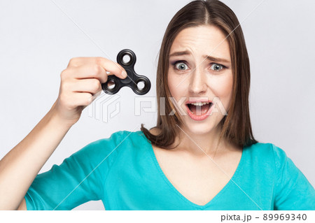 Young beautiful girl holding and playing with fidget spinner. studio shot on white background. 89969340
