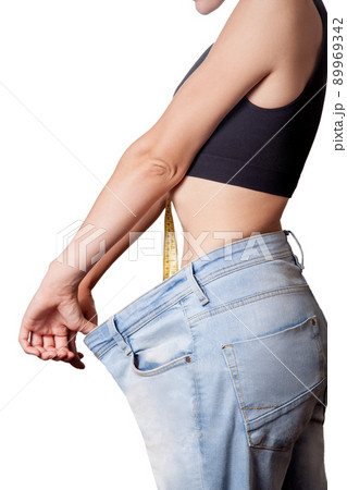 Close-up of slim waist of young woman in big jeans showing successful weight loss, isolated on white background, diet concept. 89969342