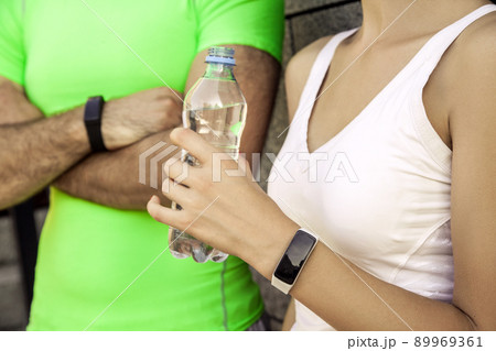 Young sporty couple are resting and check their fitness watch together, drinking water. sport and technology concepts. Young sporty couple are resting and check their fitness watch together, drinking water. sport and technology concepts. 89969361