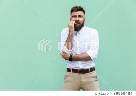 Stylish bearded businessman with warried. Hipster guy having shocked face, looking at camera. Indoor, studio shot, light green background 89969484