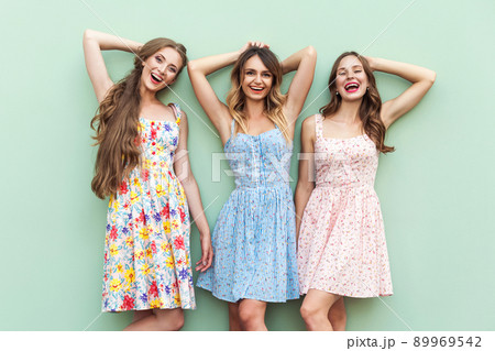 Beautiful girls in dress, standing in front of green background . Hands crossed under head, relaxed after shopping in mall. looking at camera and toothy smiling. Isolated on green background. Studio Beautiful girls in dress, standing in front of green background . Hands crossed under head, relaxed after shopping in mall. looking at camera and toothy smiling. Isolated on green background. Studio 89969542