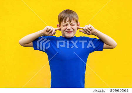 I dont want hear you! Sadness ginger boy holding fingers on ears and closed eyes. Isolated on yellow background 89969561