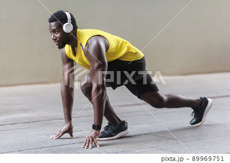 Profile view. African athlete man in running start pose. Outdoor shot, morning. Spring or summer 89969751