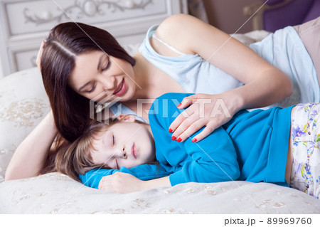Careful young mother putting down her little daughter. Happy family. Studio shot. 89969760