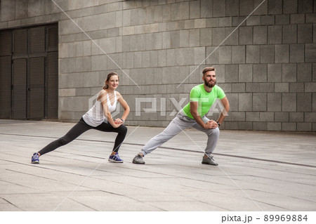 fitness, sport, exercising, training and people concept - couple doing triceps dip exercise on city street bench. fitness, sport, exercising, training and people concept - couple doing triceps dip exercise on city street bench. 89969884