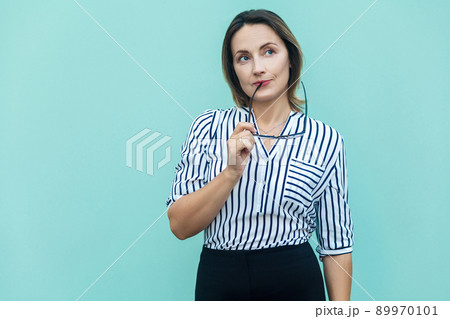 Hmm. Let my think. Blonde business woman boss wondering and imagination, and holding glasses. Studio shot on blue background 89970101