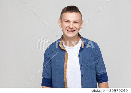 Young success man wearing blue shirt looking at camera and toothy smile. Studio shot, gray background Young success man wearing blue shirt looking at camera and toothy smile. Studio shot, gray background 89970240