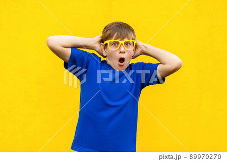 Portrait of freckled boy with shocked face. Holding hands near head, open mouth and looking at camera. Studio shot, yellow background Portrait of freckled boy with shocked face. Holding hands near head, open mouth and looking at camera. Studio shot, yellow background 89970270