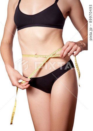 Slim fit happy young woman with measure tape measuring her waist with black underwear, isolated on white background. studio shot. 89970493