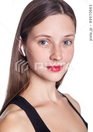 Young beautiful woman with freckles and wireless earphones on her ears. studio shot. 89970663