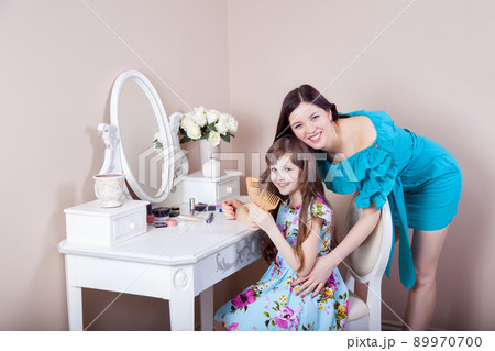 Mother hairdressing her preteen beautiful daughter at home. 89970700