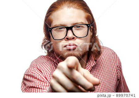 Funny bearded readhead businessman with red shirt and freckles looking at camera and pointing finger to you. studio shot isolated on white.. 89970741