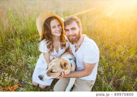 Happy beautiful couple with their Alabai dog in nature with sunset. 89970800