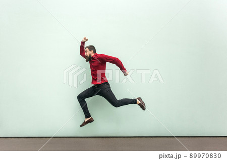 Was late for work in firs day. Young adult bearded man running to the work. Outdoor, gray wall 89970830