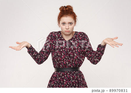 Negative human emotions, facial expressions, life perception and attitude. Puzzled redhead woman with arms out, shrugging her shoulders. Isolated studio shot on gray background. 89970831